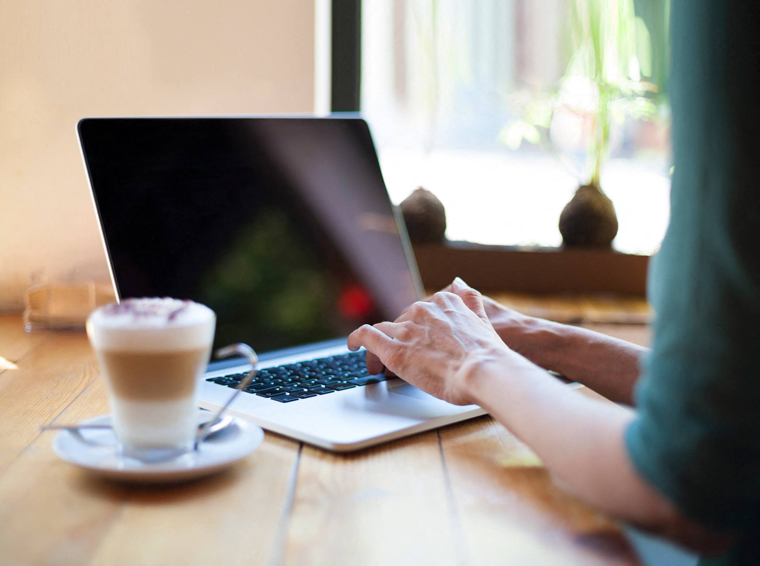 a woman typing on a laptop computer with a cup of coffee  at Tapestry Forest Creek Apartments in Collierville, TN